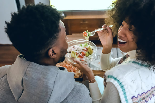 couple smiles while eating pizza and salad