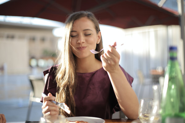woman smiles after taking bite of food