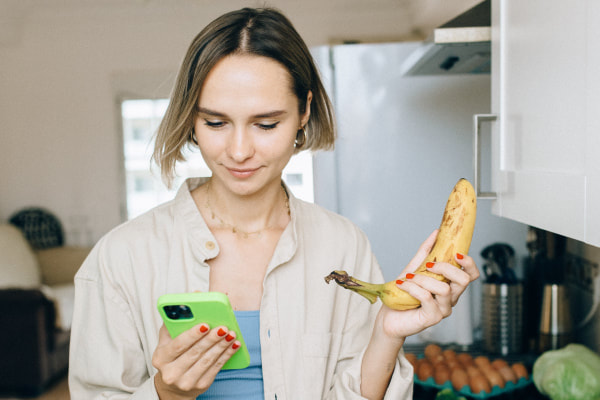 woman holds banana and looks at phone